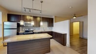 Located at 5290 Big Island Dr in Jacksonville, FL, this one-bedroom, one-bathroom residence offers a well-designed single-floor layout with a thoughtful mix of tile and hardwood-style flooring throughout. The kitchen serves as a standout feature, showcasing rich dark cabinetry, granite countertops, stainless steel appliances including a refrigerator, electric range, and built-in microwave, as well as a central island with pendant lighting overhead. A track lighting system and large windows allow ample natural light to fill the space. The open kitchen flows into the main living area, which is finished with light tile flooring and a ceiling fan. The bedroom offers warm hardwood-style flooring, a ceiling fan, and direct access to a dedicated closet with shelving, providing practical storage. The bathroom is clean and functional, featuring a tiled tub-shower combination, a toilet, and a vanity with granite countertops and dark cabinetry that mirrors the kitchen aesthetic. A hallway connects the main living areas efficiently, and the unit also includes an in-unit washer and dryer, as visible in the 3D overview. The overall design is modern and cohesive, with neutral tones and quality finishes throughout.