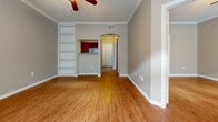 This single-floor residence offers a thoughtfully designed layout with consistent, high-quality finishes throughout. Rich hardwood flooring flows across the main living areas and bedrooms, complemented by crown molding and neutral warm-toned walls that create a cohesive and inviting atmosphere.

The kitchen is a standout feature, equipped with rich cherry wood cabinetry, granite countertops, and a full suite of stainless steel appliances including a range, built-in microwave, dishwasher, and refrigerator. Tile flooring adds practicality to this well-organized cooking space. A pass-through connects the kitchen to the living area, enhancing the open feel.

The living room is generously sized, anchored by built-in shelving on one wall and a ceiling fan overhead. An arched passageway leads to the entryway, while French doors topped with an arched transom window allow abundant natural light to fill the room and provide outdoor access.

The bedrooms feature the same warm hardwood flooring and crown molding, with arched panel doors and ample wall space. Each room is well-proportioned and benefits from the home's consistent design language.

The bathroom is finished with large-format tile flooring, white cabinetry, granite countertops, a wide vanity mirror, and a glass-enclosed shower-tub combination, offering a clean and functional space.