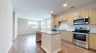Located at 7326 Wallace Rd in Charlotte, NC, this single-floor unit offers a clean, modern design with a cohesive aesthetic carried throughout every room. The open-concept layout connects the kitchen and living area seamlessly, creating a bright and functional common space. The kitchen is well-appointed with light wood cabinetry, a subway tile backsplash, granite countertops, and a full suite of stainless steel appliances, including a refrigerator, range, microwave, and dishwasher. A central island with a granite top provides additional prep space and a natural focal point for the room. Multiple windows allow natural light to fill the living area, offering views of the surrounding neighborhood. Light wood-tone luxury vinyl plank flooring runs throughout the entire unit, lending warmth and continuity to the space. The bedrooms are generously sized, with large windows, neutral wall tones, and ceiling fans for comfort. The bathroom features a full soaking tub and shower combination, wood-tone vanity with granite counters, and clean white fixtures. The overall ambiance of the unit is bright, contemporary, and move-in ready, reflecting thoughtful design choices suited for comfortable everyday living.
