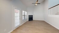 Located in Clearwater, FL, this two-story home offers a thoughtfully designed layout spread across two floors. The main level features an open-plan living and kitchen area filled with natural light from multiple windows and a glass exterior door. The living room showcases vaulted ceilings, light wood-look flooring, a corner fireplace, and a ceiling fan, creating a bright and airy atmosphere. The kitchen is well-appointed with rich, dark wood cabinetry, granite countertops, a subway tile backsplash, stainless steel appliances including a refrigerator, dishwasher, microwave, and range, plus recessed lighting overhead. A staircase connects the main level to the upper floor, where both carpeted bedrooms are located. Each bedroom features a ceiling fan and ample natural light. The generously sized primary bedroom includes a walk-in closet with built-in wire shelving alongside an additional bi-fold door closet. The full bathroom is outfitted with wood cabinetry, a marble-topped vanity with modern brushed nickel fixtures, and a glass-enclosed shower. Wood-look flooring continues through the bathroom, complementing the clean, neutral finishes found throughout the home.