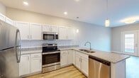 This single-story unit in Clarksville, Indiana offers a thoughtfully designed layout that maximizes its compact footprint. The kitchen serves as a standout feature, showcasing white shaker-style cabinetry, granite countertops, a classic subway tile backsplash, and a full suite of stainless steel appliances, including a refrigerator, range, microwave, and dishwasher. Pendant lighting accents the peninsula, which provides additional prep space and casual seating opportunities. Light wood-tone flooring runs throughout the main living areas, contributing to a bright, cohesive aesthetic.

The living area benefits from natural light and direct outdoor access through a set of French doors. The bedroom is carpeted for comfort, features a ceiling fan, a window for natural light, and includes a closet with a built-in rod and shelving for storage. The bathroom is well-appointed with wood-look flooring, a granite-topped vanity with dark cabinetry, and a full tub-shower combination. Neutral wall tones throughout the unit create a clean, move-in-ready environment suited for a range of décor styles.