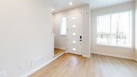 Located at 2445 Yukon Dr in Longmont, CO, this two-story home offers a thoughtfully designed layout spread across two levels. The lower level, which includes an attached garage with an automatic door opener and interior access, serves as a practical entry point to the home. A bright, modern entryway with light hardwood flooring and a contemporary front door with glass panel inserts welcomes residents and guests, allowing natural light to filter in.

The upper level hosts the main living areas, including a kitchen and living room combination that forms the heart of the home. The kitchen is outfitted with rich, dark wood cabinetry featuring black hardware, white quartz countertops, a subway tile backsplash, and a full suite of stainless steel appliances. Light hardwood floors carry throughout this level, complementing the clean, neutral color palette.

The two bedrooms are carpeted and receive natural light through large windows with outdoor views. The generously sized primary bedroom includes a closet. Three bathrooms serve the home, including one with subway tile tub surround, wood-toned vanity, and matte black fixtures, and a compact half bath on the lower level. Overall, the home presents a clean, modern aesthetic with quality finishes throughout.