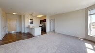 Located at 116–138 Centre St in Malden, Massachusetts, this single-floor residential unit offers a thoughtfully designed open-concept layout that seamlessly connects the kitchen and living areas. The kitchen is outfitted with dark espresso cabinetry, stainless steel appliances including an electric range, microwave, and refrigerator, complemented by a white breakfast bar peninsula and sleek pendant lighting overhead. Hardwood-style flooring anchors the kitchen and entry areas, while plush carpeting extends throughout the living room and bedrooms, adding warmth and comfort underfoot. The generously sized living area receives abundant natural light through large windows that frame views of the surrounding Malden cityscape. The bedrooms are well-proportioned, each featuring carpeted floors, broad windows, and ample closet storage — including double closets in the primary bedroom. The bathrooms are finished in a clean, modern aesthetic with dark vanity cabinetry, white countertops, large mirrors with overhead lighting, and tile flooring. Windows in the bathrooms allow for natural light and ventilation. Neutral tones throughout the unit create a bright, cohesive ambiance that is both functional and inviting, making this a well-rounded residential space in the heart of Malden.