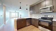 This well-designed 1-bedroom, 1-bathroom unit offers a thoughtful layout spread across a single floor, combining comfort and modern style throughout. Light wood-tone flooring runs continuously through every room, creating a cohesive and airy feel.

The open-concept kitchen and living area serves as the heart of the unit. The kitchen is outfitted with rich dark brown cabinetry, white quartz countertops, a subway tile backsplash, and a full suite of stainless steel appliances including a range, microwave, dishwasher, and refrigerator. A peninsula with pendant lighting above it defines the kitchen space while maintaining a seamless connection to the living area, which features a ceiling fan and access to natural light from nearby windows.

The bedroom is a generously proportioned retreat, featuring dual windows that frame outdoor views and invite ample natural light. A ceiling fan adds comfort, and the room connects conveniently to a dedicated closet for storage.

The bathroom is cleanly appointed with a dark wood double vanity topped with a white countertop, a large mirror, and a soaking tub with vertically tiled surround. Light flooring ties the space together with the rest of the unit.

Overall, the unit presents a clean, contemporary aesthetic with quality finishes and a practical, well-organized floor plan.