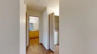 Located in Airway Heights, WA, this 2-bedroom, 1-bathroom unit offers a practical and comfortable single-floor layout. The living room serves as the heart of the home, featuring a fireplace, plush carpeting, and a sliding glass door that opens to a private balcony with views of the surrounding neighborhood. A large window allows natural light to fill the space. Adjacent to the living area, the dining room and kitchen are designed for everyday functionality. The kitchen is fully equipped with light wood cabinetry, ample counter space, a range, dishwasher, refrigerator, and wood-look vinyl flooring. Both bedrooms are carpeted and well-lit; the primary bedroom offers a comfortable footprint, while the second bedroom features a window with neighborhood views. The shared bathroom includes a wood-toned vanity with storage, a large mirror with overhead lighting, and a shower with a curtain surround, all finished with wood-look flooring. A utility room with a stacked washer and dryer adds everyday convenience. Throughout the unit, a neutral color palette and clean finishes create a bright and cohesive atmosphere.