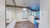 Located at 12100 Metric Blvd in Austin, TX, this one-bedroom, one-bathroom unit offers a well-organized single-floor layout designed to maximize every square foot. The open-concept kitchen is a standout feature, showcasing dark espresso cabinetry, light quartz countertops, a full suite of stainless steel appliances including a refrigerator, electric range, and built-in microwave, complemented by a subway tile backsplash. A peninsula with a stainless steel sink adds prep space and serves as a natural divider between the kitchen and living area. Hardwood-style flooring flows throughout the main living and kitchen spaces, lending warmth and continuity. The bedroom is generously proportioned with soft carpeting underfoot, a ceiling fan with light fixture, and a large window with blinds that invites ample natural light. A hallway connects the main living areas to the private spaces. The bathroom features a soaking tub and shower combination with white tile and a bold black accent tile border, paired with dark wood cabinetry for storage and wood-style flooring that ties the space together. The overall aesthetic is modern and cohesive, with a neutral palette that provides a clean, move-in-ready feel.