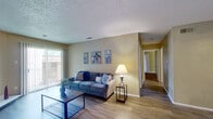 This single-story, 2-bedroom, 1-bathroom home offers a practical and comfortable layout designed to maximize every square foot. The living room serves as the heart of the space, featuring light hardwood-style flooring, a textured ceiling, a fireplace, and a sliding glass door that floods the room with natural light and provides access to an outdoor area. A connecting hallway leads to the rest of the home, maintaining a smooth flow throughout.

The dining room is positioned adjacent to the kitchen and features matching hardwood-style floors, a ceiling fan with light fixture, and warm neutral wall tones. The galley-style kitchen is efficiently arranged with white cabinetry, light countertops, a double sink, and black appliances including a refrigerator, electric range, dishwasher, and microwave.

Both bedrooms are carpeted and offer a quiet, comfortable retreat. The spacious primary bedroom includes large vertical-blind-covered sliding doors, while the second bedroom features a window with blinds, providing natural light. The shared full bathroom is equipped with a tub-shower combination featuring white tile surround, wood-style flooring, a vanity with granite-style countertop, and textured walls throughout.