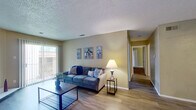 This single-story, 2-bedroom, 1-bathroom home offers a practical and comfortable layout designed to maximize every square foot. The living room serves as the heart of the space, featuring light hardwood-style flooring, a textured ceiling, a fireplace, and a sliding glass door that floods the room with natural light and provides access to an outdoor area. A connecting hallway leads to the rest of the home, maintaining a smooth flow throughout.

The dining room is positioned adjacent to the kitchen and features matching hardwood-style floors, a ceiling fan with light fixture, and warm neutral wall tones. The galley-style kitchen is efficiently arranged with white cabinetry, light countertops, a double sink, and black appliances including a refrigerator, electric range, dishwasher, and microwave.

Both bedrooms are carpeted and offer a quiet, comfortable retreat. The spacious primary bedroom includes large vertical-blind-covered sliding doors, while the second bedroom features a window with blinds, providing natural light. The shared full bathroom is equipped with a tub-shower combination featuring white tile surround, wood-style flooring, a vanity with granite-style countertop, and textured walls throughout.