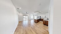 This well-designed 2-bedroom, 2-bathroom single-story unit offers a thoughtfully planned layout with modern finishes throughout. Light wood-look flooring flows continuously across the entire space, creating a cohesive and clean aesthetic. Recessed lighting is featured in every room, complementing the bright, white walls that give the unit an open, airy feel.

The kitchen is a standout feature, showcasing a two-tone design with rich walnut-finish lower cabinets and crisp white upper cabinetry. A marble-look tile backsplash, white quartz countertops, stainless steel appliances, and a central island with a dual-basin sink complete this functional and stylish space. Industrial-style pendant lights add a modern touch overhead.

Both bedrooms are bright and comparably sized, each equipped with ceiling fans and windows that bring in natural light. The primary bedroom connects to a walk-in closet outfitted with built-in shelving, hanging rods, and a built-in dresser.

Each bathroom mirrors the unit's modern design language, featuring walnut vanities, white quartz countertops, round mirrors, and black matte fixtures. One bathroom includes a soaking tub with a sliding glass enclosure, while the other features a frameless glass walk-in shower with marble-look tile surround. A dedicated laundry room with a full-size washer and dryer adds everyday convenience.