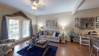 Located at 5555 Long Prairie Trace in Richmond, TX, this single-floor residence offers a thoughtfully designed layout that balances comfort and functionality. The open-concept living and dining area serves as the heart of the home, featuring warm hardwood-style flooring, a ceiling fan, and large windows and French doors that invite abundant natural light and outdoor views. The adjacent kitchen is well-appointed with rich dark wood cabinetry, a mosaic tile backsplash, black appliances including a refrigerator, range, and dishwasher, a double-basin sink, and a breakfast bar with seating — ideal for casual dining or entertaining. The bedrooms offer carpeted flooring, ceiling fans, and generous windows that bring in natural light. The primary bedroom is a spacious retreat with room for a king-sized bed and matching nightstands. The bathrooms are finished with dark wood vanity cabinetry, hardwood-style flooring, and neutral warm-toned walls. One bathroom features a tub-shower combination, while the other includes a single-sink vanity with overhead cabinetry. Throughout, the residence maintains a cohesive warm neutral palette, creating an inviting and comfortable atmosphere well-suited to everyday living.