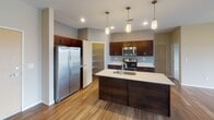 Located at 3227 43rd Ave NE in Bismarck, North Dakota, this single-floor residence offers a well-designed open-concept layout that seamlessly connects the kitchen, dining, and living areas. The kitchen is a standout feature, showcasing rich dark-stained cabinetry, light quartz-style countertops, and a full suite of stainless steel appliances including a side-by-side refrigerator, electric range, and built-in microwave. A central island with an undermount sink and pendant lighting overhead adds both functionality and visual appeal. A walk-in pantry provides generous storage. Wood-style flooring flows throughout the main living areas, complementing the neutral color palette, while a sliding glass door leads to a private balcony with outdoor views.

The living area is generously proportioned, bathed in natural light from large windows. Bedrooms are carpeted for comfort, each featuring windows that overlook the surrounding neighborhood. The primary bathroom includes a walk-in shower and an adjacent walk-in closet with built-in shelving, while a second full bathroom offers a tub-shower combination. Throughout the unit, brushed nickel fixtures and clean finishes contribute to a cohesive, modern aesthetic.