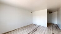 Located at 2550 West Hazelwood Street in Phoenix, AZ, this single-story, 2-bedroom, 1-bathroom unit offers a practical and well-maintained layout. Light wood-style laminate flooring runs throughout the home, lending a clean and cohesive aesthetic to every room. The living area is bright and open, with a front entry door alongside a window fitted with vertical blinds that frame views of palm trees, reflecting the classic Phoenix surroundings. The kitchen is efficiently designed with blue-gray upper and lower cabinetry, light countertops, a double sink, and white appliances including a dishwasher, electric range, and refrigerator — providing all essential functionality. The spacious primary bedroom offers generous floor space with a closet, while the second bedroom features a window that allows natural light to fill the room. A hallway connects the living areas to the full bathroom, which includes a vanity with a large mirror, blue-gray cabinetry, and a shower-tub combination. A dedicated closet provides additional storage. Neutral white walls throughout keep the interior feeling fresh and versatile, making this an efficient and move-in ready home.