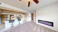 This single-floor residence offers a thoughtfully designed layout across a comfortable footprint, featuring 2 bedrooms and 3 bathrooms. The open-concept living and kitchen area serves as the heart of the home, highlighted by a sleek, wall-mounted electric fireplace and a ceiling fan overhead. The kitchen is outfitted with white cabinetry, stainless steel appliances including a gas range and microwave, and a center island with bar seating illuminated by stylish black-and-gold pendant lights. Tile flooring transitions seamlessly into plush carpet throughout the living and bedroom areas.

The spacious primary bedroom features a ceiling fan, multiple windows that invite natural light and outdoor views, and access to a well-appointed en suite bathroom complete with a dual-sink vanity, backlit mirror, white cabinetry, and a walk-in shower. The second bedroom is bright with its own windows and ceiling fan. A second full bathroom mirrors the clean, modern aesthetic with a single vanity, backlit mirror, and a shower-tub combination. A tiled entryway provides a welcoming transition into the home, complemented by a dedicated hallway and closet for added storage.