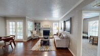 This thoughtfully designed single-floor residence offers 2 bedrooms, 3 bathrooms, and a functional layout that makes excellent use of its space. The living room serves as the heart of the home, showcasing rich hardwood flooring, crown molding, a textured ceiling, and a classic fireplace flanked by built-in shelving. Multiple windows with blinds allow natural light to fill the room, creating a warm and inviting ambiance.

The kitchen is a standout feature, equipped with stainless steel appliances, white shaker-style cabinetry, a subway tile backsplash, and granite countertops that extend to a breakfast bar peninsula — ideal for casual dining or entertaining. The adjacent dining area benefits from hardwood flooring, crown molding, and access to the exterior via French doors.

The bedrooms are carpeted and comfortably sized, with the primary bedroom offering direct sightlines to the kitchen. Each room is served by one of three bathrooms, which include tiled shower/tub combinations. Two closets provide dedicated storage throughout the residence. The overall palette of neutral grays and warm wood tones creates a cohesive, modern aesthetic across all rooms.
