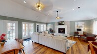 Located at 1 Turtle Lake Dr in Birmingham, Alabama, this single-floor property offers a thoughtfully designed layout that balances comfort and functionality. The main living area is anchored by soaring vaulted ceilings and a striking white brick fireplace, creating a warm and inviting focal point. Rich hardwood flooring flows throughout, complementing the sage green walls that lend a calm, cohesive aesthetic. Multiple sets of French doors line the living space, flooding the room with natural light and providing views of the surrounding outdoor areas. Brass pendant lighting and ceiling fans add stylish finishing touches overhead.

Adjacent to the living room, the dining area features vaulted ceilings of its own and centers around a natural live-edge wood dining table, with additional French doors offering continued access to the outdoors. Glass-paned interior French doors connect the dining space seamlessly to the living room.

The galley-style kitchen is well-equipped with warm wood cabinetry, dark countertops, black appliances, crown molding, and a peninsula that provides additional seating.

A dedicated fitness room rounds out the layout, outfitted with rubber flooring, free weights, resistance equipment, and large windows that bring in natural light and outdoor views — making it a standout feature of this versatile property.