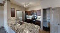 This 610 square foot apartment in Austin, TX, offers a blend of modern amenities and efficient design. The single-story unit features two bedrooms, including a primary bedroom of 120 square feet, and one bathroom. The open-concept living area is highlighted by a tray ceiling with wood trim, adding architectural interest and a sense of height to the space.

The kitchen is a standout feature, boasting granite countertops, stainless steel appliances, and dark wood cabinetry. A tile backsplash adds a stylish touch, while the layout allows for easy meal preparation and entertaining. The living room flows seamlessly from the kitchen, creating a spacious feel. Large windows and glass doors allow ample natural light to flood the space, enhancing the sense of openness.

Both bedrooms offer comfortable living spaces, with the primary bedroom providing a generous 120 square feet. The bathroom features a clean, modern design with white tiling and a shower/tub combination. Throughout the apartment, neutral wall colors and wood-look flooring create a cohesive, contemporary aesthetic.

Additional features include a ceiling fan for improved air circulation, window blinds for privacy, and built-in closet space for storage. The apartment's efficient layout maximizes the use of its 610 square feet, making it an ideal choice for those seeking a modern, low-maintenance living space in Austin.