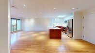 Located on Beacon Street in the heart of Brookline, MA, this single-floor residence offers a thoughtfully designed open layout that maximizes both functionality and comfort. The expansive living and kitchen area serves as the centerpiece of the home, where warm hardwood floors extend throughout and recessed lighting creates a bright, welcoming ambiance. The contemporary kitchen is outfitted with rich walnut-toned lower cabinetry contrasted by sleek white upper cabinets with glass-front accents, white quartz countertops, stainless steel appliances, and a generous island with an integrated sink — all illuminated by a skylight overhead. The open floor plan allows for seamless flow between the kitchen and the spacious living area. The bedrooms feature the same handsome hardwood flooring, crown molding, and windows that frame greenery and neighborhood views, filling each room with natural light. The bathrooms are finished with light tile flooring, white cabinetry, and accessible fixtures including grab bars, reflecting thoughtful design. A well-connected hallway links all rooms efficiently, and the overall layout — as visible in the floorplan — provides a logical, comfortable flow throughout the residence.