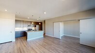 This single-floor unit is designed with a modern, open-concept layout that integrates the kitchen and living areas into one cohesive, well-lit space. The kitchen is a standout feature, equipped with dark espresso cabinetry extending to the ceiling for ample storage, a white subway tile backsplash, and a full suite of stainless steel appliances, including a French door refrigerator, electric range, and microwave. A central island with a granite countertop and undermount sink doubles as a casual dining and prep area, illuminated by pendant lighting overhead. Recessed lighting and wood-style luxury vinyl plank flooring extend throughout the open living area, which benefits from a sliding glass door leading to a private balcony with exterior views.

The bedroom is carpeted for comfort and features a wide window that brings in natural light and outdoor views. The bathroom is finished consistently with the rest of the unit, incorporating granite counters, dark cabinetry, wood-style flooring, and a tub-shower combination. The overall palette of warm neutrals, dark wood tones, and clean white trim creates a cohesive, contemporary aesthetic throughout the space.