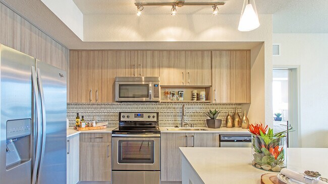 Cocina de lujo en apartamento con gabinetes de madera, electrodomésticos de acero inoxidable y encimeras de cuarzo. - Griffis North Olive