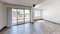 Located at 34 S Main Street in Wilkes-Barre, PA, this single-floor unit offers a practical and well-organized layout designed for comfortable everyday living. The open living area is finished with durable wood-style laminate flooring and neutral white walls, creating a bright and clean atmosphere. A ceiling fan provides added comfort, while large sliding glass doors lead to a private balcony, flooding the space with natural light and offering open outdoor views of the surrounding area. An additional window further enhances the sense of airiness in the living space. The kitchen is situated just off the main living area and is equipped with dark wood cabinetry featuring classic knob hardware, light granite-style countertops, a stainless steel sink, a black electric range with an overhead ventilation hood, and a black refrigerator. The layout is compact yet functional, providing ample storage through both upper and lower cabinets. The bathroom is neatly appointed with a rich cherry-toned wood vanity, a white integrated sink with mirrored medicine cabinet above, and a lighted vanity fixture. The wood-style flooring continues throughout, maintaining a cohesive aesthetic across the entire unit. This straightforward, move-in-ready space combines practicality with comfortable finishes in a convenient Wilkes-Barre location.