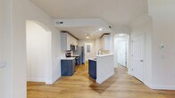 This three-story home offers a thoughtfully designed layout spread across three distinct levels. The ground floor provides an attached garage with automatic opener, offering secure parking and additional storage. The main living level serves as the heart of the home, showcasing an open-concept kitchen and living room highlighted by warm hardwood-style flooring throughout. The kitchen features two-tone cabinetry — navy blue lower cabinets paired with light upper cabinets — complemented by white quartz countertops, stainless steel appliances including a refrigerator, range, microwave, and dishwasher, plus a peninsula for additional workspace. A pantry and dedicated laundry area add everyday convenience. The living room is anchored by a classic white-framed fireplace and large windows that invite natural light and views of surrounding greenery. A balcony extends the living space outdoors, overlooking lush landscaping. The upper floor houses both bedrooms, including a spacious primary suite with its own closet. The two bathrooms are finished with gray shaker-style cabinetry, white countertops, large mirrors, and hardwood-style flooring, with one featuring a sliding-glass enclosed shower. Carpeted staircases connect each level, and multiple closets provide ample storage throughout.
