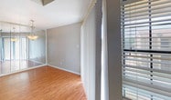 Located at 7415 Tallow Wind Trl in Fort Worth, Texas, this single-floor residence offers a well-organized layout with a mix of practical finishes and comfortable living spaces throughout. The living room is a standout area, boasting soaring vaulted ceilings that create a sense of openness and volume. A bank of elevated windows along the upper wall floods the space with natural light, while recessed lighting and plush carpeting add warmth and comfort underfoot. Vertical blinds and window treatments provide privacy while maintaining the bright, airy feel. The kitchen is equipped with dark espresso cabinetry offering ample storage, light-toned countertops, and black appliances including a refrigerator and electric range, all set atop warm wood-look flooring that extends through the adjacent areas. The bedrooms feature soft carpeting, generous closet space with mirrored sliding doors, and large windows that bring in views of the surrounding neighborhood. A ceiling fan with light fixture provides comfort in one of the bedrooms. The bathroom includes a full tub and shower combination with clean white tile surround. Overall, the space presents a neutral, move-in-ready palette with functional design throughout.