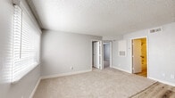 Located at 1050 N Camino Seco in Tucson, Arizona, this single-story home offers four bedrooms and one bathroom within a compact, efficiently designed floor plan. The interior features a mix of light wood-look vinyl plank flooring in the main living and kitchen areas, complemented by plush carpeting throughout the bedrooms, creating a comfortable and cohesive feel.

The galley-style kitchen is outfitted with white cabinetry, light stone-pattern countertops, a stainless steel sink, and white appliances including a range and refrigerator — making practical use of the available space. A ceiling fan in the main living area adds comfort, while a front entry door with natural light from a side window provides a welcoming entry point.

The spacious primary bedroom includes a generous closet with a full hanging rod and shelving. The additional bedrooms each feature carpeted floors, textured ceilings, and windows with blinds that allow for natural light and privacy. One bedroom includes an open built-in shelving unit, offering convenient storage.

The bathroom is well-appointed with wood-look flooring, a wide vanity with a light stone countertop, a large mirror, and warm overhead lighting. Throughout the home, neutral gray walls and white trim create a clean, move-in ready aesthetic suited for Tucson's sunny desert setting.