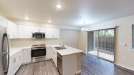 Located at 501 NE 112th Ave in Vancouver, Washington, this well-designed two-bedroom, one-bathroom single-story home offers a thoughtful layout with modern finishes throughout. The open-concept kitchen, dining, and living area serves as the heart of the home, featuring white shaker cabinetry, stainless steel appliances including a refrigerator, range, microwave, and dishwasher, and a peninsula with a double sink and extended counter — ideal for both meal prep and casual dining. A pendant chandelier and sliding glass door leading to a private patio bring in natural light and provide easy outdoor access. Wood-look vinyl flooring runs through the main living and wet areas, creating a clean, cohesive look. Both bedrooms are carpeted and include ceiling fans and closets with built-in rods for storage. The primary bedroom offers generous proportions, while the second bedroom features a window with outdoor views. The full bathroom is well-appointed with a wide double-sink vanity, white cabinetry, and a tub/shower combo. A dedicated laundry room houses a full-size front-loading washer and dryer with overhead shelving. Four closets throughout the home provide ample storage for everyday living.