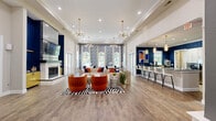 Located at 221 Fairforest Way in Greenville, SC, this single-floor clubhouse space delivers a bold and sophisticated aesthetic from the moment you enter. The grand entryway greets visitors with soaring ceilings, decorative lattice panels, and a striking geometric tile inlay underfoot, all illuminated by an elegant globe chandelier. The open-concept living area flows naturally from the entry, offering a welcoming lounge with ample room for gathering and relaxation.

The full kitchen is outfitted with stainless steel appliances, crisp white cabinetry, sleek gray countertops, and a long breakfast bar lined with modern white barstools. Bold navy geometric wallpaper and stylish pendant lighting give the kitchen a vibrant, contemporary energy.

The dining area is a true showpiece, wrapped in dramatic art deco-inspired wallpaper and flanked by a series of tall arched windows that flood the room with natural light and provide views of the surrounding greenery. Flowing white curtains frame each window, enhancing the room's elegant ambiance.

Throughout the space, wide-plank hardwood-style flooring ties each area together cohesively. Glass-paneled French doors provide visual connectivity between zones while maintaining a sense of defined purpose in each room. The overall design balances modern boldness with refined detail.