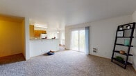 This single-floor residence offers a practical and comfortable layout designed for everyday living. The open living area is spacious and carpeted, filled with natural light from multiple windows and a large sliding glass door that leads to a balcony, offering pleasant views of surrounding greenery and trees. A wall-mounted heater and clean white walls contribute to the room's bright, airy feel.

The kitchen is thoughtfully designed with warm honey-toned wood cabinetry arranged in an L-shape, providing ample storage. White appliances — including a refrigerator, range, and dishwasher — are included, and the space features durable wood-style flooring and a pass-through counter that connects to the living area.

The bedrooms are generously sized with plush carpeting, neutral walls, and natural light from windows with views of mature trees. Each bedroom includes closet space, with at least one featuring a walk-in style closet with built-in shelving.

Two bathrooms serve the residence, each featuring wood-style flooring and warm wood vanity cabinetry with white countertops. One bathroom includes a standalone shower stall, while the other offers a vanity with a large mirror. The overall ambiance of the space is clean, functional, and comfortable.