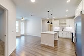 Located at 1223 East Plant Street in Winter Garden, FL, this well-appointed 2-bedroom, 2-bathroom residence offers a thoughtfully designed single-floor layout. The open-concept living, dining, and kitchen area serves as the heart of the home, featuring wide-plank wood-style flooring, recessed lighting, and a ceiling fan that enhance the bright, airy atmosphere. The kitchen is a standout, equipped with white shaker cabinetry, a marble-style subway tile backsplash, quartz countertops, stainless steel appliances, a dedicated pantry, and a central island illuminated by sleek pendant lights with matte black accents. The generously sized primary bedroom features plush carpeting, a ceiling fan, natural light from a large window, and a walk-in closet with built-in wire shelving. The second bedroom is equally well-lit with hardwood-style flooring. Both bathrooms are finished in a clean, modern aesthetic with white subway tile, quartz vanities, and wood-look tile flooring. Additional highlights include three closets, an in-unit laundry area, and a private balcony with a dark metal railing offering views of lush landscaping and the surrounding neighborhood — a perfect outdoor retreat in the Florida sunshine.