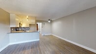 Located at 1020 N Magnolia Ave in Anaheim, California, this well-appointed one-bedroom, one-bathroom unit offers a thoughtfully designed single-floor layout. The open-concept kitchen and living area creates a welcoming, functional space anchored by warm wood-look flooring that extends throughout. The kitchen is a standout feature, equipped with stainless steel appliances including a gas range and over-the-range microwave, crisp white shaker cabinets, stone-look countertops, and a striking blue-and-white mosaic tile backsplash that adds a modern touch. A ceiling fan overhead and a peninsula counter seamlessly connect the kitchen to the spacious living area, which offers generous room for furnishings and benefits from neutral gray walls and a textured ceiling. The bedroom is a comfortable retreat highlighted by a distinctive wood-paneled accent wall, a ceiling fan with a window allowing natural light, and direct access to a dedicated walk-in closet outfitted with dual clothing rods and shelving. The bathroom includes a full tub-shower combination with clean white surround. A hallway connects all spaces efficiently, completing this practical and stylish layout ideal for comfortable everyday living.