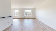 Located at 1301 Dundas St W in Mississauga, this 2-bedroom, 1-bathroom unit offers a clean, modern aesthetic across a thoughtfully designed single-floor layout. Light-toned hardwood-style flooring runs throughout the space, complementing the crisp white walls and trim that give the unit a bright, airy feel.

The open-concept kitchen and living area forms the heart of the unit. The kitchen is well-appointed with white shaker-style cabinetry, a subway tile backsplash, stainless steel appliances including a refrigerator, stove, and microwave, and a central island with a dark countertop that provides both prep space and a casual dining area. The living room extends generously from the kitchen, bathed in natural light from multiple windows that frame views of the surrounding greenery.

Both bedrooms are comfortably sized, with the primary bedroom offering ample space and closet access. Each room features the same warm flooring and neutral palette, with windows that invite natural light and views of the outdoors. The second bedroom also includes closet storage.

The bathroom is finished with classic white subway tile surrounding a full soaking tub with chrome fixtures, maintaining the clean and timeless design language found throughout the unit. Hallways connecting the rooms are well-proportioned, contributing to a smooth and functional flow across the entire layout.