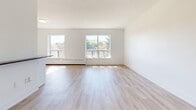 Located at 1301 Dundas St W in Mississauga, this 2-bedroom, 1-bathroom unit offers a clean, modern aesthetic across a thoughtfully designed single-floor layout. Light-toned hardwood-style flooring runs throughout the space, complementing the crisp white walls and trim that give the unit a bright, airy feel.

The open-concept kitchen and living area forms the heart of the unit. The kitchen is well-appointed with white shaker-style cabinetry, a subway tile backsplash, stainless steel appliances including a refrigerator, stove, and microwave, and a central island with a dark countertop that provides both prep space and a casual dining area. The living room extends generously from the kitchen, bathed in natural light from multiple windows that frame views of the surrounding greenery.

Both bedrooms are comfortably sized, with the primary bedroom offering ample space and closet access. Each room features the same warm flooring and neutral palette, with windows that invite natural light and views of the outdoors. The second bedroom also includes closet storage.

The bathroom is finished with classic white subway tile surrounding a full soaking tub with chrome fixtures, maintaining the clean and timeless design language found throughout the unit. Hallways connecting the rooms are well-proportioned, contributing to a smooth and functional flow across the entire layout.