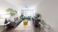 This single-floor residence offers a thoughtfully designed open-concept layout with modern finishes throughout. The kitchen serves as a functional centerpiece, featuring light wood-tone cabinetry, stainless steel appliances including a range, microwave, and dishwasher, quartz countertops with a tile backsplash, and pendant lighting. The kitchen flows seamlessly into the dining area, which accommodates a round marble-top table, and further into the living room. The living room is generously proportioned, bathed in natural light from large windows dressed with white blinds and sheer curtains, and equipped with a ceiling fan overhead. Wood-style flooring extends throughout the main living areas, adding warmth and cohesion. The bedrooms offer a calm retreat with soft neutral walls, natural light from large windows, and carpeted floors. The primary bathroom is well-appointed with a glass-enclosed walk-in shower featuring tile surround, a dual-sink vanity with quartz countertops, wood-tone cabinetry, and light tile flooring. A dedicated in-unit laundry closet houses a full-size side-by-side washer and dryer with overhead shelving. The overall aesthetic is contemporary and cohesive, with neutral tones and clean lines throughout.