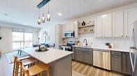 Located at 709 First Ave SW in Rochester, MN, this well-appointed one-bedroom, one-bathroom residence offers a thoughtfully designed single-floor layout. The open-concept kitchen and living area forms the heart of the home, featuring two-tone cabinetry with white upper cabinets and gray lower cabinets, stainless steel appliances, a subway tile backsplash, open floating shelves, and a central island with a white quartz countertop and bar seating beneath stylish pendant lighting with a dark wood accent beam. Light wood-tone flooring runs throughout the main living areas, adding warmth and continuity. The living room is bright and inviting, with a large sliding glass door that opens to a private balcony offering outdoor views. The bedroom is a comfortable retreat with large windows that bring in natural light and direct views of the surrounding area, complemented by plush carpet flooring. The full bathroom features light wood-tone flooring, a gray vanity with ample storage, and a full tub-shower combination with black hardware accents. Additional conveniences include two closets and a dedicated utility room, providing practical storage and functional living support throughout.