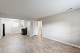 This single-floor unit offers a straightforward, functional layout with a clean and modern aesthetic throughout. The open living area flows directly into the kitchen, both finished with light-toned luxury vinyl plank flooring that lends a bright, cohesive feel to the shared space. Neutral gray walls and crisp white trim are consistent throughout, creating a calm and move-in-ready atmosphere.

The kitchen is well-equipped, featuring white cabinetry that extends to the ceiling for ample storage, a stainless steel sink, a gas range, and a black refrigerator. A window above the back door brings in natural light, enhancing the clean, functional design of the space.

The bedrooms are carpeted in a warm beige tone and feature multiple windows that allow generous natural light to filter in, offering views of the surrounding greenery. The rooms provide comfortable, versatile spaces suited for a variety of furniture arrangements.

The bathroom is finished with white tile surrounding a full tub-shower combination, complemented by a window that adds ventilation and light. Chrome fixtures complete the clean, utilitarian design.

An entry door with a panel design provides a clear threshold from the outside. Throughout the unit, consistent neutral tones, practical finishes, and an efficient use of space define the overall character of this well-maintained property.