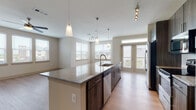 This well-appointed 2-bedroom, 2-bathroom residence is laid out on a single floor, offering a thoughtful and functional floor plan. A welcoming hallway with light wood-style flooring leads into the main living areas, setting a clean and modern tone throughout.

The open-concept kitchen is a standout feature, showcasing a large center island with granite countertops, an undermount sink, and sleek pendant lighting overhead. Dark wood cabinetry provides generous storage, while stainless steel appliances—including a refrigerator, range, microwave, and dishwasher—complete the space. Track lighting adds additional illumination, and multiple windows flood the area with natural light. French doors open directly to a private balcony, extending the living space outdoors.

The living area flows naturally from the kitchen, featuring light wood-style flooring, a ceiling fan, and additional windows that bring in ample daylight. Both bedrooms are carpeted and equipped with ceiling fans, offering a comfortable and quiet retreat. Each bedroom benefits from natural light through well-positioned windows.

Both bathrooms are finished with marble-style tile flooring, granite-topped dark wood vanities, framed mirrors, and generous storage cabinetry—delivering a refined, cohesive aesthetic. The overall ambiance of the unit is bright, modern, and move-in ready.