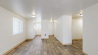 This single-floor unit offers a clean, functional layout designed for comfortable everyday living. The open main area seamlessly connects the living space to the kitchen, all finished with durable wood-look vinyl plank flooring and crisp white walls that create a bright, welcoming atmosphere. Natural light filters in through multiple windows fitted with horizontal blinds, and a sliding glass door in the living area provides additional light and outdoor access.

The galley-style kitchen is efficiently arranged with white appliances including a refrigerator, electric range, and dishwasher, complemented by wood-toned cabinetry, light countertops, and a window above the sink. The bedrooms feature soft wall-to-wall carpeting, individual windows with natural views, and baseboard heating. At least one bedroom includes a spacious reach-in closet with a hanging rod. Two bathrooms serve the unit — one featuring a stand-up shower and the other a full shower/tub combination — both finished with wood-look flooring, vanity with storage, and clean white fixtures throughout. The overall design emphasizes practicality and ease of maintenance, with a neutral palette that offers a versatile backdrop for any interior style.