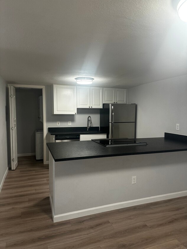 Modern black and white kitchen with stainless glass cooktop, oven, dishwasher and refrigerator. - 12170 Huron St
