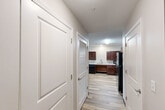 Located at 100 Codell Drive in Lexington, Kentucky, this single-floor, one-bedroom, one-bathroom unit offers a thoughtfully designed layout with consistent light wood-style flooring flowing throughout every room. The combined kitchen and living area forms the heart of the space, with the kitchen featuring rich dark-stained wood cabinetry, granite-style countertops, black appliances including a range, refrigerator, microwave, and dishwasher, alongside a double-basin sink. A full-glass exterior door in the living area allows natural light to fill the room and provides outdoor access. The open living area is finished with a ceiling fan and neutral-toned walls, creating a clean and versatile environment. The bedroom is a comfortable, well-proportioned room with a ceiling fan, a window with blinds for natural light and privacy, and the same warm wood-style flooring. The hallway connects the rooms efficiently, with louvered doors offering access to closet or utility storage. The bathroom is notably spacious and ADA-accessible, equipped with grab bars, a combination tub and shower with a handheld showerhead, a dark-wood vanity with a stone-style countertop, and ample open floor space. The overall design is clean, modern, and functional.