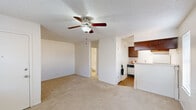 Located at 5010 S Urbana Ave in Tulsa, Oklahoma, this one-bedroom, one-bathroom unit offers a practical and efficient single-floor layout. The living area is carpeted and bathed in natural light from a pair of windows, with a ceiling fan providing comfortable air circulation beneath a textured ceiling. A wall-mounted air conditioning unit ensures year-round climate control. The open sightlines from the living space extend toward both the kitchen and the bathroom, creating a connected and easy-to-navigate layout. The kitchen is compact yet well-equipped, featuring warm wood cabinetry, light countertops, a full-size refrigerator, an electric coil range, and parquet-style flooring that adds a touch of character. The spacious primary bedroom accounts for the majority of the unit's total floor area, offering generous room for furnishings and everyday living. Two closets provide ample storage throughout the unit. The bathroom is clean and straightforward, featuring a tiled tub-shower combination with a curved curtain rod, a toilet, and a vanity. Neutral white walls and light-toned finishes throughout give the space a bright, clean aesthetic that is easy to personalize.