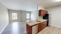 Located at 25-47 Prospect St in Milford, CT, this well-appointed one-bedroom, one-bathroom unit offers a practical and comfortable single-floor layout. The galley-style kitchen is a standout feature, equipped with rich cherry-toned cabinetry, granite countertops, stainless steel appliances including a gas range, dishwasher, and refrigerator, and light hardwood-style flooring that extends into the adjacent living area. A peninsula with a sink provides additional counter space and creates a seamless transition into the open living area, which is brightened by multiple windows that invite natural light throughout. The living space is generous in scale, offering a clean, neutral palette with light gray walls and light-toned flooring. The bedroom is a comfortable retreat, finished with plush carpeting, a natural light-filled window, and direct access to a dedicated walk-in closet. The bathroom maintains the same design consistency seen throughout the unit, featuring tile flooring, a cherry-toned vanity with a granite countertop, and clean white finishes. Overall, the space presents a cohesive, modern aesthetic with quality finishes and a functional layout suited to everyday living.