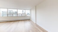 Located at 484 Avenue Rd in Toronto's prestigious Avenue Road corridor, this bright three-bedroom, one-bathroom unit offers a well-designed single-floor layout. The interior is finished with light wood flooring throughout the living and bedroom areas, complemented by crisp white walls that enhance the sense of openness. Large floor-to-ceiling windows in the bedrooms flood the space with natural light and frame sweeping views of the Toronto skyline, including the surrounding midtown cityscape.

The generously sized primary bedroom features mirrored sliding closet doors that add depth and reflect the natural light. Additional bedrooms are equally well-appointed, each with mirrored closets and access to natural light. The hallways connect the rooms efficiently, contributing to a functional and practical layout.

The kitchen is finished with white cabinetry accented by brushed gold hardware, a white rectangular tile backsplash, light quartz countertops, and a distinctive gold undermount sink — a refined touch that elevates the overall aesthetic. The bathroom continues the upscale feel with large-format marble-effect wall tiles surrounding the tub and shower area. Light porcelain tile flooring and a pedestal sink complete the clean, modern look throughout this well-appointed Toronto residence.