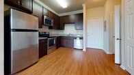 Located at 2110 Arden Creek Way in Charlottesville, Virginia, this single-floor residence offers a thoughtfully designed layout with a cohesive aesthetic throughout. The kitchen is a standout feature, showcasing rich dark-stained cabinetry that extends to the ceiling, granite-style countertops, and a full suite of stainless steel appliances including a refrigerator, electric range, built-in microwave, and dishwasher. Light hardwood-style flooring runs through the kitchen and flows into the adjacent living and dining area, where crown molding, a ceiling fan, and multiple windows with horizontal blinds create a bright, comfortable atmosphere. Plush neutral carpeting covers the bedrooms, each of which benefits from natural light admitted through sizable windows with views of surrounding greenery. Crown molding accents add a refined touch to several rooms. The bathroom features tile flooring, a dark wood vanity with an integrated sink and mirrored cabinet above, and clean, neutral wall tones consistent with the rest of the home. Overall, the space presents a neutral, move-in-ready palette with practical finishes throughout.