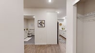 Located in Seattle's Seward Park neighborhood, this thoughtfully designed 2-bedroom, 2-bathroom residence offers a clean, contemporary aesthetic across a well-organized single-floor layout. Warm wood-look flooring flows throughout the main living areas, complemented by crisp white walls and recessed lighting that keeps the space feeling bright and open.

The living room is a welcoming gathering space featuring a wall-mounted mini-split HVAC system and expansive sliding glass doors that flood the room with natural light and provide access to an outdoor area. Both bedrooms are comfortably sized, each featuring large windows with roller shades that allow for flexible light control and views of the exterior. The primary bedroom offers ample space for a full bedroom suite, while both rooms benefit from dedicated closets for storage.

The two bathrooms are finished with large-format gray tile flooring and white cabinetry. One bathroom features a glass-enclosed walk-in shower with white subway tile, while the other includes a soaking tub/shower combination and accessibility-friendly grab bars. The kitchen showcases white shaker-style cabinetry and modern appliances. A central hallway connects all rooms efficiently, rounding out a practical and polished floor plan ideal for everyday living.