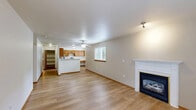 Located in Auburn, WA, this 1-bedroom, 1-bathroom single-floor unit offers a thoughtfully arranged layout with comfortable living spaces throughout. The open living room is a standout, featuring warm light wood-style flooring, a classic white-mantled fireplace, and a window that fills the room with natural light — creating a welcoming, cozy atmosphere. The well-equipped kitchen includes warm oak cabinetry, light stone countertops, and stainless steel appliances including a refrigerator, electric range, and dishwasher. A dining nook adjacent to the kitchen benefits from its own window with greenery views outside. The bedroom is generously sized with plush carpeting, a sliding glass door opening to a private patio with a natural rock backdrop, and access to two closets for ample storage. The bathroom features a full tub-shower combo, a wood-toned vanity, and light flooring. A dedicated in-unit laundry area accommodates a full-size washer and dryer. Warm wood trim throughout ties the space together, offering a consistent and inviting aesthetic from room to room.