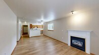 Located in Auburn, WA, this 1-bedroom, 1-bathroom single-floor unit offers a thoughtfully arranged layout with comfortable living spaces throughout. The open living room is a standout, featuring warm light wood-style flooring, a classic white-mantled fireplace, and a window that fills the room with natural light — creating a welcoming, cozy atmosphere. The well-equipped kitchen includes warm oak cabinetry, light stone countertops, and stainless steel appliances including a refrigerator, electric range, and dishwasher. A dining nook adjacent to the kitchen benefits from its own window with greenery views outside. The bedroom is generously sized with plush carpeting, a sliding glass door opening to a private patio with a natural rock backdrop, and access to two closets for ample storage. The bathroom features a full tub-shower combo, a wood-toned vanity, and light flooring. A dedicated in-unit laundry area accommodates a full-size washer and dryer. Warm wood trim throughout ties the space together, offering a consistent and inviting aesthetic from room to room.