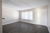 Located at 1495 Peterson Ave in Long Beach, California, this single-floor, 2-bedroom, 1-bathroom unit offers a practical and well-designed layout. Throughout the space, wood-look laminate flooring and neutral gray-toned walls create a clean, cohesive aesthetic.

The living room is an open, light-filled space featuring a large window with horizontal blinds that allows ample natural light. It flows seamlessly into the dining area, which is separated from the kitchen by a half-wall breakfast bar — a functional design detail that maintains an open feel while defining each zone.

The galley-style kitchen is efficiently laid out with white shaker cabinets, dark countertops, a double stainless steel sink, and stainless steel appliances including a gas range and refrigerator. Dark hardwood-style flooring grounds the kitchen's crisp, modern finishes.

Both bedrooms feature ceiling fans, wood-look flooring, and windows that bring in natural light. Each bedroom includes its own closet, with the primary bedroom featuring a mirrored sliding-door closet with built-in shelving.

The bathroom is clean and functional, finished with white tile surrounding a full bathtub and shower combo, a single vanity with sink, and a small window for ventilation. The unit's compact footprint is efficiently utilized throughout.
