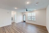 Located in Jacksonville, FL, this well-designed single-story home offers three bedrooms, two bathrooms, and a thoughtfully organized layout across a comfortable footprint. The open-concept kitchen and living area serves as the heart of the home, featuring light wood-grain cabinetry, a large white quartz island with an integrated double sink, and a full suite of stainless steel appliances including a range, microwave, and French door refrigerator. Wood-look plank flooring runs throughout the main living areas, giving the space a clean, contemporary feel. The living room benefits from natural light through a large window and direct access to an exterior door, along with a ceiling fan overhead. The three bedrooms are carpeted for comfort and each features ceiling fans and windows with horizontal blinds that invite natural light and outdoor views. The primary bedroom includes double panel doors leading to a dedicated closet. The two bathrooms are finished in a crisp, modern style — one featuring a glass-enclosed walk-in shower with wood-look flooring, and the other offering a full tub-shower combination with tiled surround and chrome fixtures. Clean white walls and consistent finishes throughout give the home a cohesive, move-in-ready appeal.